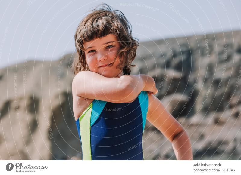 Cute girl in swimsuit standing against rocky cliff child adjust nature cloudless enjoy vacation summer positive kid lanzarote parrot beach spain europe sea