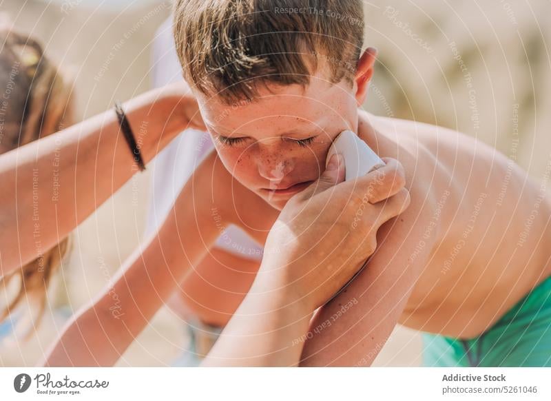 Crop woman applying sunscreen on boys face child protect care sea shore nature kid lanzarote parrot beach spain europe sunshine childhood swimwear recreation