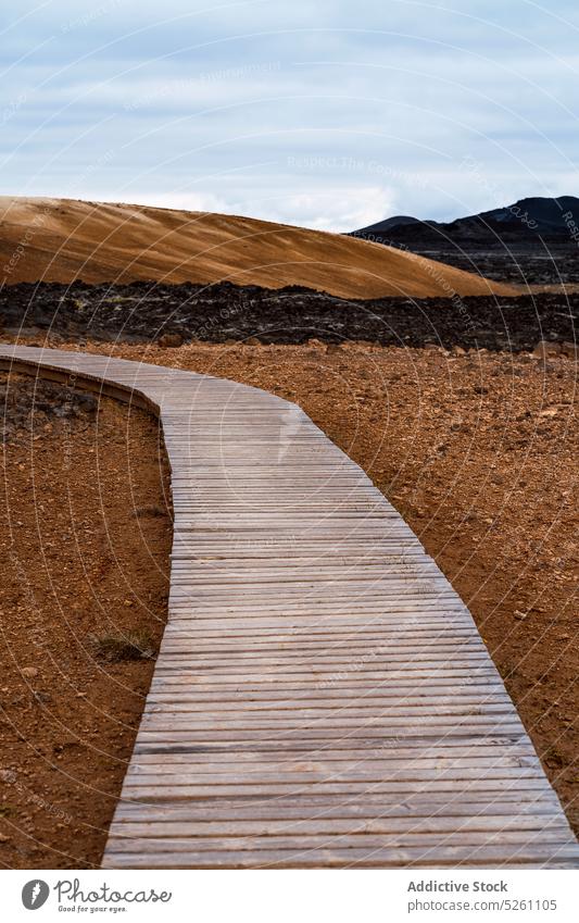 Empty roadway among hills in countryside walkway empty nature pathway landscape cloudy ground sand iceland europe terrain wooden scenic calm tranquil