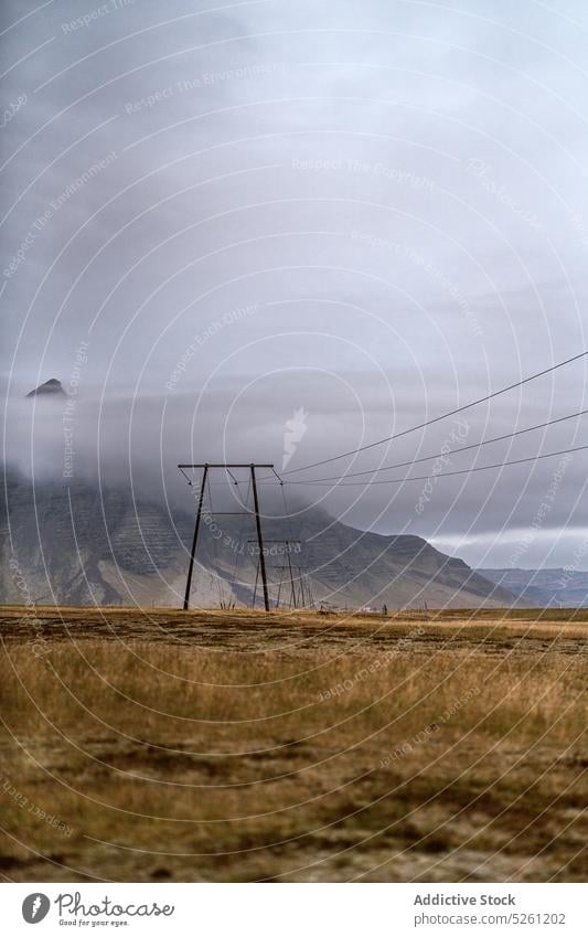 Rocky mountain near dry grassy meadow under overcast sky landscape valley field nature highland rocky ridge picturesque cloudy countryside range peak scenic