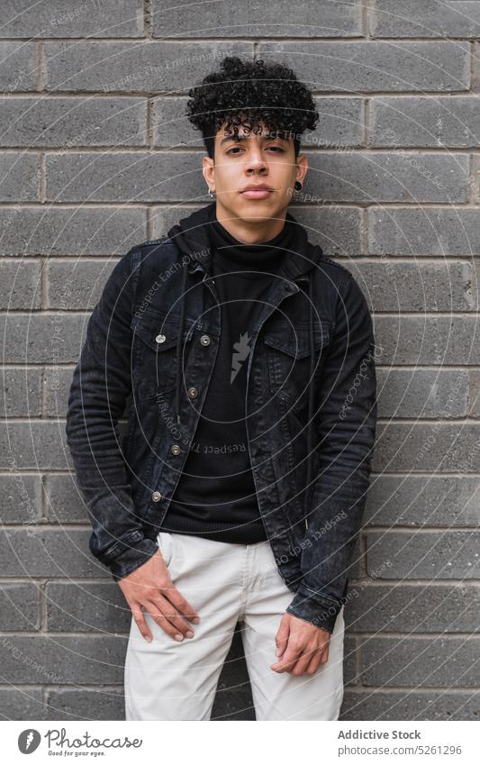 Positive Hispanic migrant guy leaning on brick wall man portrait student immigrate lifestyle street positive confident hispanic casual ethnic latin american