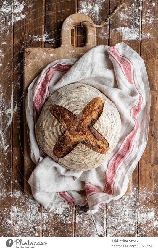 Baked bread loaf on table in flour wheat baked rustic bakery sourdough homemade crust artisan food fresh natural kitchen mess whole wooden tasty cuisine organic