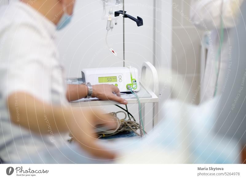 Anesthetist giving anesthesia to patient before operation in a clinic. Anesthesiologist observing the monitor readings while the patient is being anesthetized while surgery operation