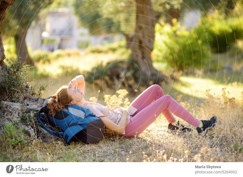 Young woman hiking in countryside. Girl is lying under the tree and having rest and relax. Concepts of adventure, extreme survival, orienteering. Backpacking hike