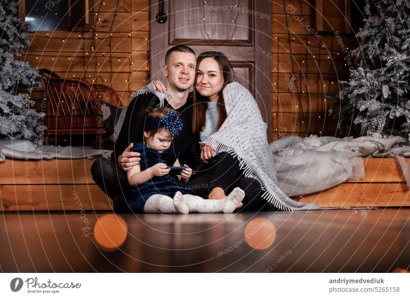 Mother, father with daughter are celebrating Christmas and new year. Parents and little child having fun near Christmas tree indoors. The morning before Xmas. Portrait close up