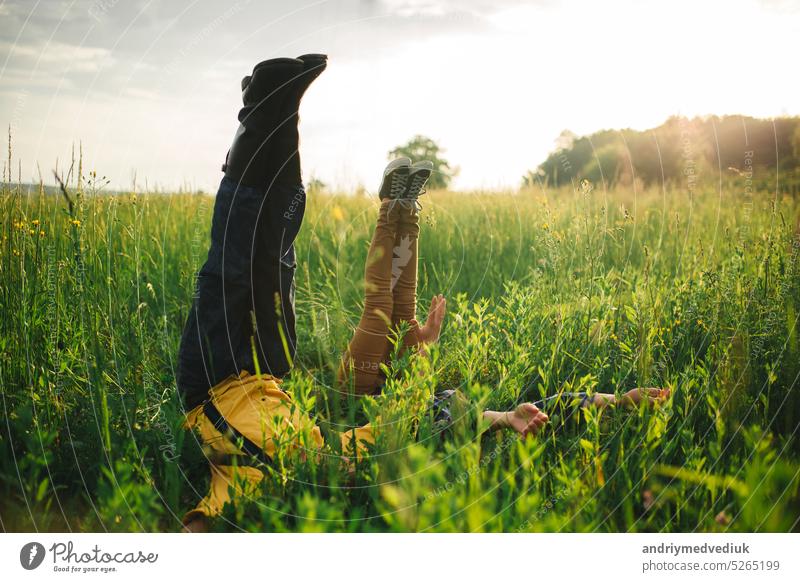 woman and man having fun outdoors. Loving hipster couple walking in the field, kissing and holding hands, hugging, lying in the grass and lifting their legs up in the summer at sunset. valentines day