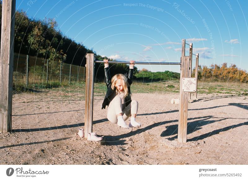 Cheerful girl hanging on bar kid having fun play playful game enjoy sports ground energy child weekend little childhood cute sunlight shadow playground carefree