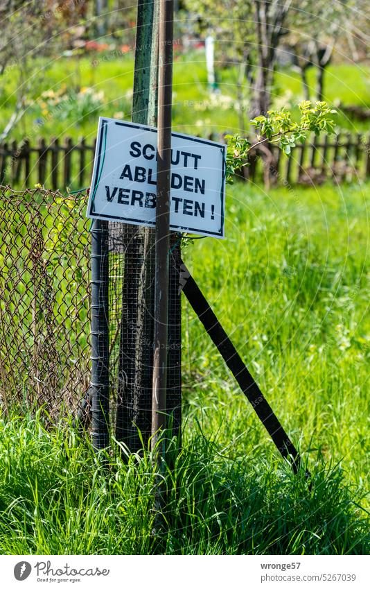 Sign SHELTER UNLOADING PROHIBITED ! stuck on a garden fence forbidden Prohibition sign Garden fence stake Fence post Debris dumping prohibited Bans