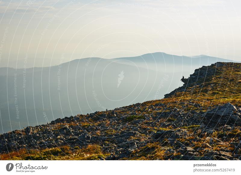 Man looking at sunrise. Mountains at sunrise. Man standing on peak. Natural mountain landscape with illuminated misty peaks, foggy slopes and valleys hiker