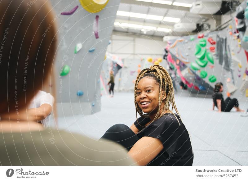 Multi-Cultural Group Of Friends Chatting By Climbing Wall In Indoor Activity Centre bouldering group friends friendship watching climber climbing center centre