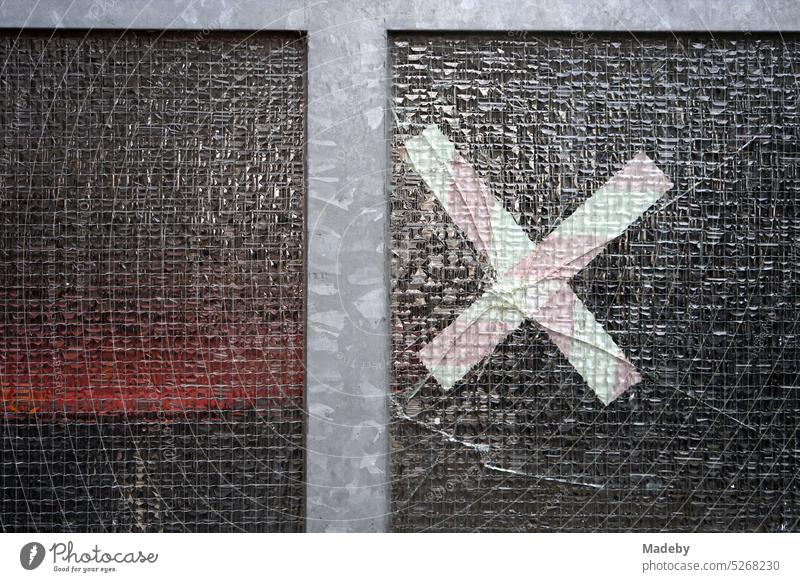 Solid front door made of untreated gray steel with ribbed glass and crack in the glass repaired with white tape in Berger Straße in the Bornheim district of Frankfurt am Main in Hesse, Germany