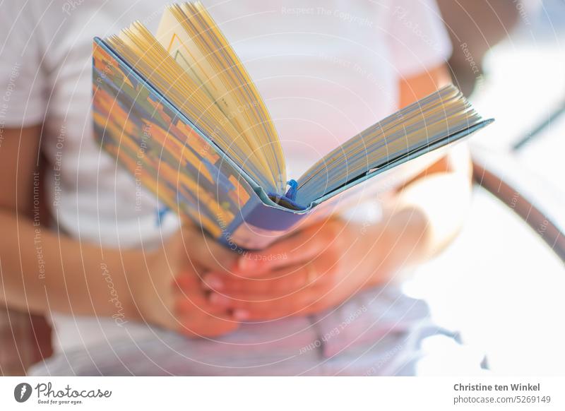 A young woman sits outside in the sun and reads a book Book Literature Sit Reading Living or residing Leisure and hobbies Cozy relaxation Woman Relaxation