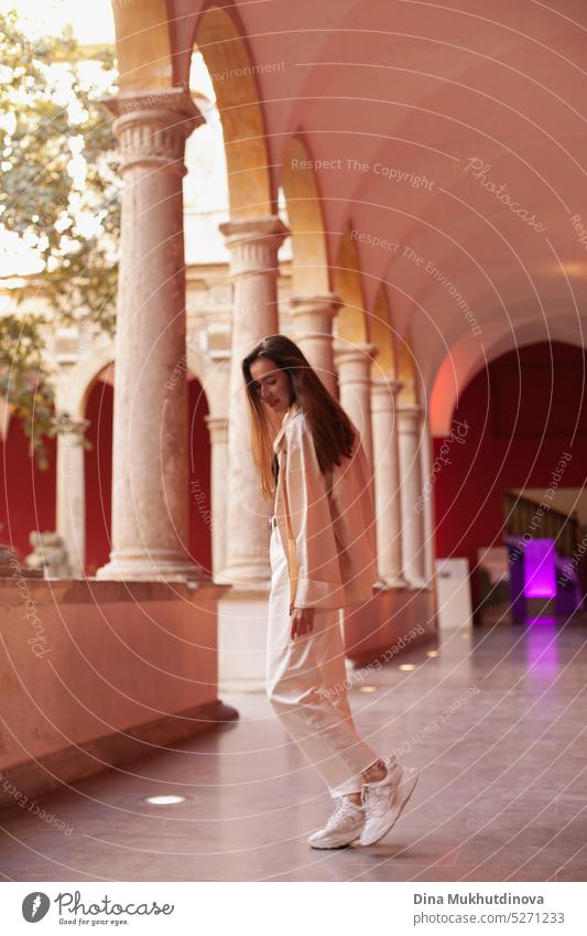 Young woman walking inside the beautiful historic building. Female tourist in modern art museum. millennial urban model fashion yellow wall city tourism young