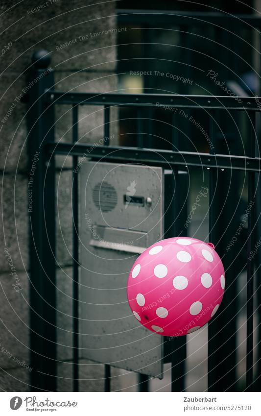 Red balloon with white dots on garden gate indicates children's birthday, although a bit gloomy Balloon points White Goal Childrens birthsday somber celebration