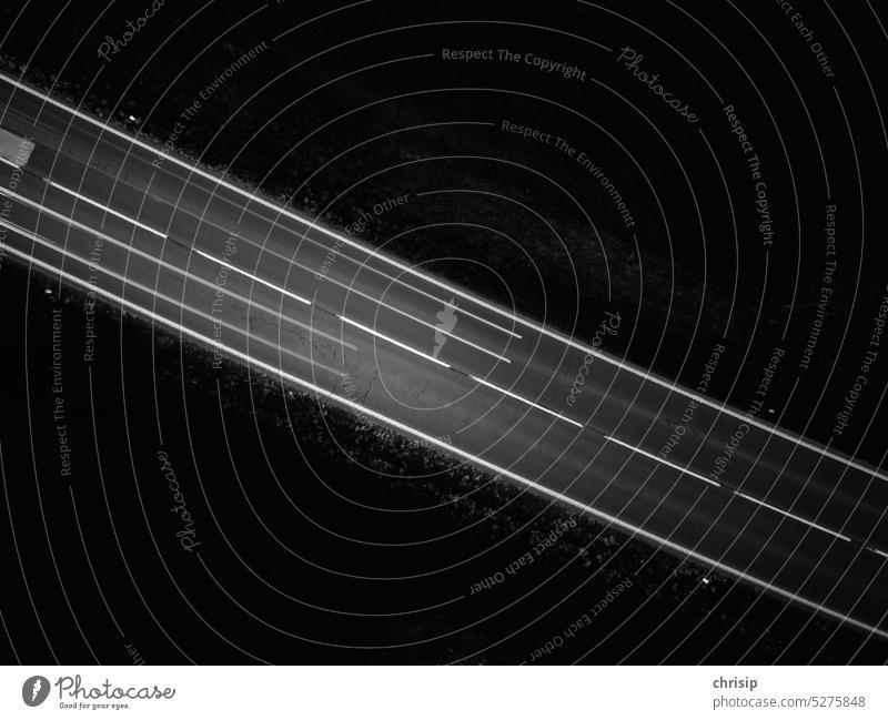 Leuchtstreifen auf Landstraße Straße dunkel finster Verkehr Schwarzweiß Drohnenfoto menschenleer