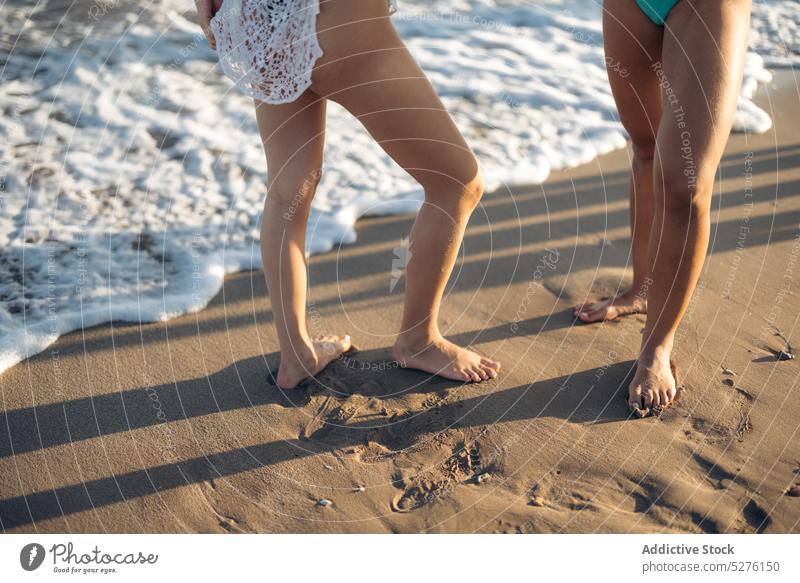 Crop women standing near sea girlfriend beach wave sand summer vacation water weekend female couple together coast barefoot friendship holiday foam seaside