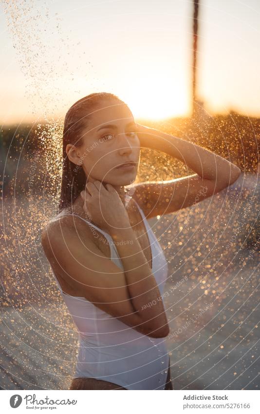 Woman taking shower on beach near sea woman sunset wash wet hair tourist weekend summer resort female young seaside sundown coast vacation evening dusk paradise