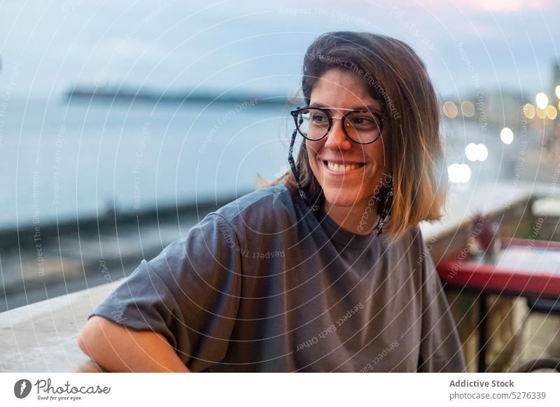 Smiling woman sitting in outdoor cafe cafeteria sea sunset relax evening twilight sundown freedom female smile young enjoy positive harmony casual traveler