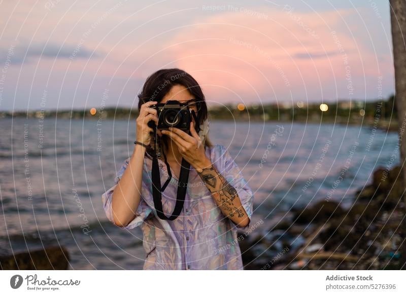 Young female traveler taking a photo woman camera sea sunset water vacation evening ripple twilight sundown calm dusk sky young ocean casual cuba summer shore