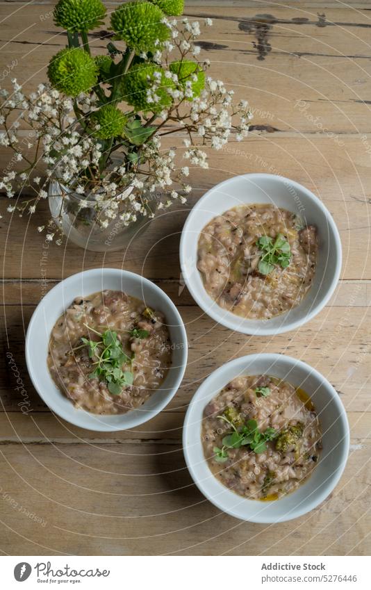 Bowls with porridge near blooming flowers breakfast healthy food meal bowl vase bouquet natural ceramic fresh cook glass delicious cereal tasty wooden dish