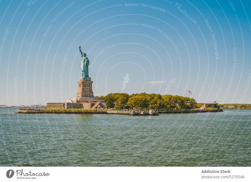 Famous monument on seafront in sunlight statue of liberty embankment cityscape famous water blue sky cloudless landmark river new york liberty island usa