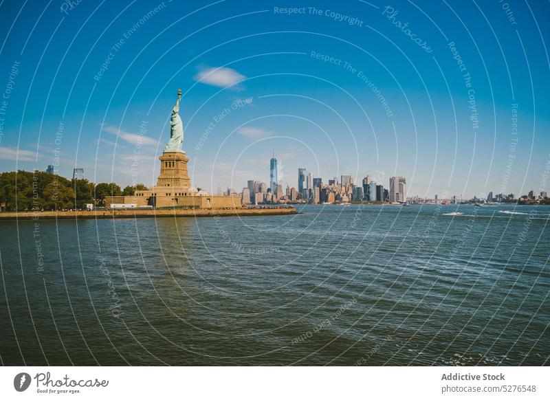 Famous monument on seafront in sunlight statue of liberty embankment cityscape famous water blue sky cloudless landmark river new york liberty island usa