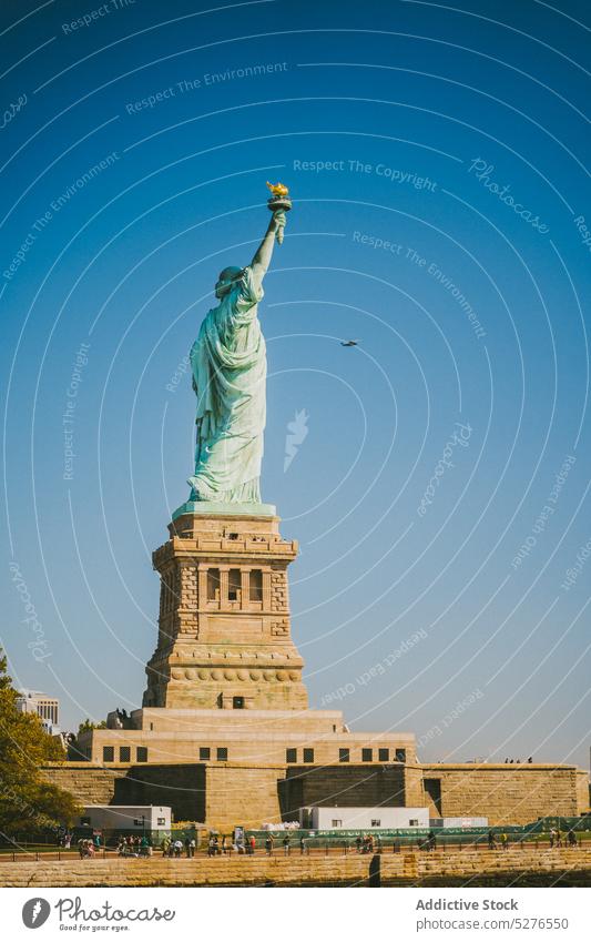 Famous monument on seafront in sunlight statue of liberty embankment cityscape famous water blue sky cloudless landmark river new york liberty island usa