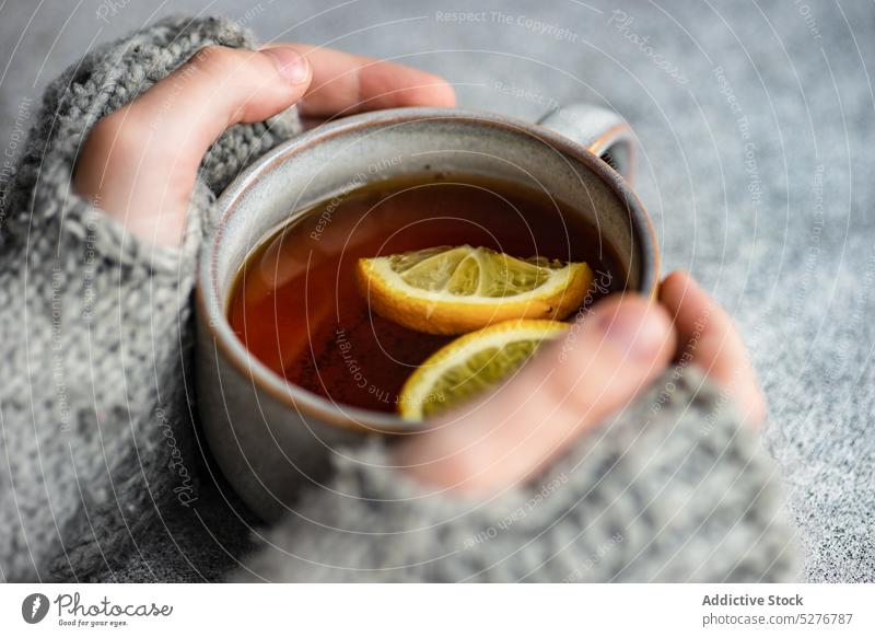 Kid hands hold cup of tea background beverage black child citrus cloves cold season concrete delicious drink grey healthy hot kid knit knitted lemon mitten mug