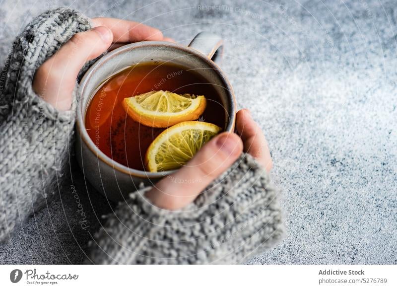 Kid hands hold cup of tea background beverage black child citrus cloves cold season concrete delicious drink grey healthy hot kid knit knitted lemon mitten mug