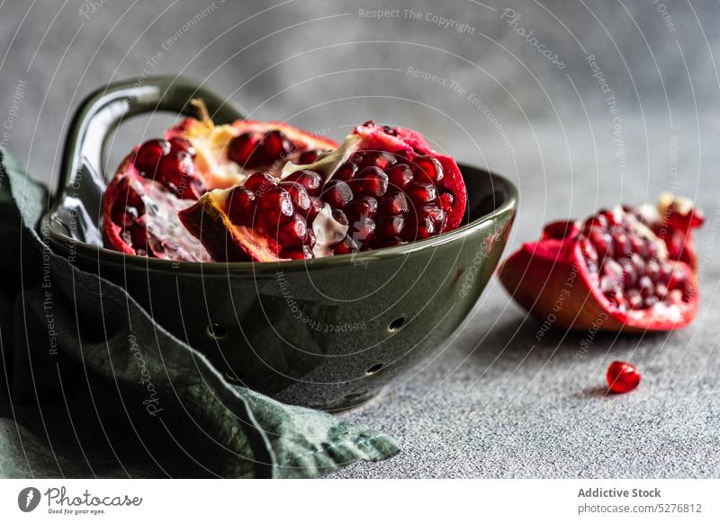 Minimalistic pomegranate raw fruit background bowl ceramic concept concrete dessert diet eat food gourmet grey group half healthy meal minimalism napkin natural