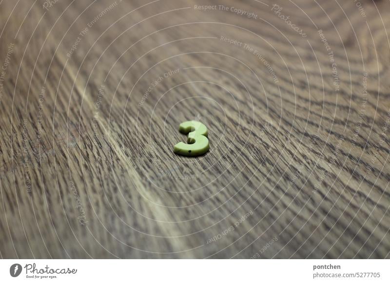 a small, yellow, 3 plastic on wood three number Numbers I count to three Digits and numbers Signs and labeling Colour photo pedagogy Wood Wood grain oak wood