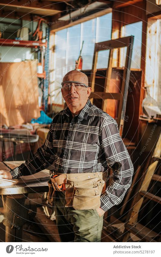 Senior craftsman looking at camera in workshop carpenter joinery professional job artisan male woodwork lumber senior aged timber woodworker carpentry