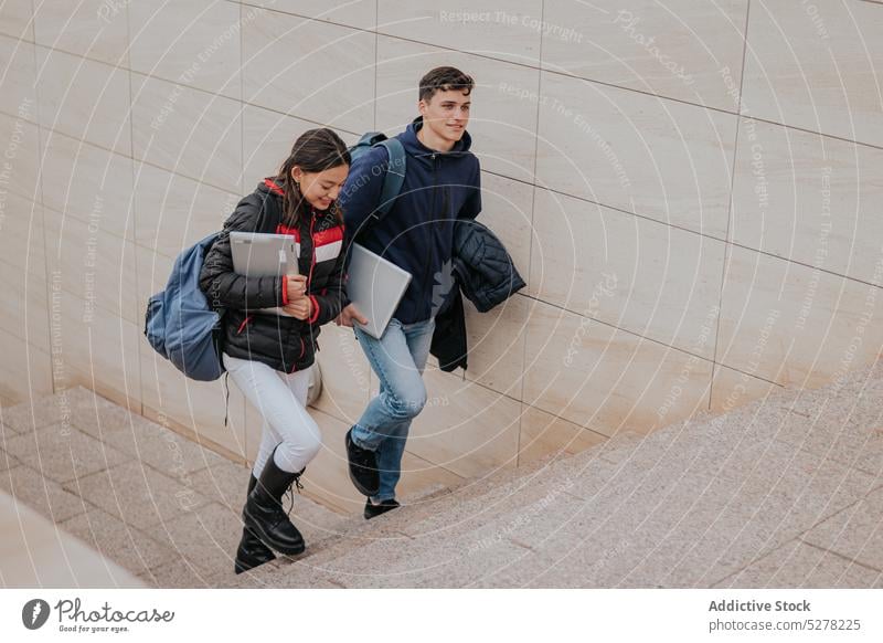 Cheerful students climbing up stairs together laptop study friend campus smile university positive young friendship cheerful college classmate group walk happy