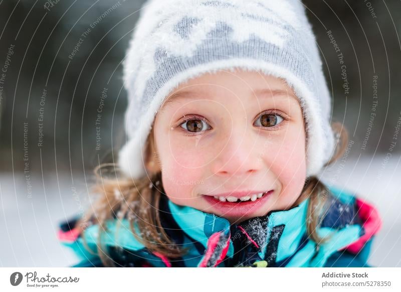 Smiling girl in winter forest snowfall happy smile woods nature enjoy cheerful outerwear hat season warm clothes cold kid glad pleasure wintertime child