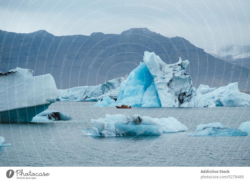 Boat floating in sea near icebergs motorboat water mountain gray shore travel explore iceland expedition vessel transport breathtaking north scenic marine ridge