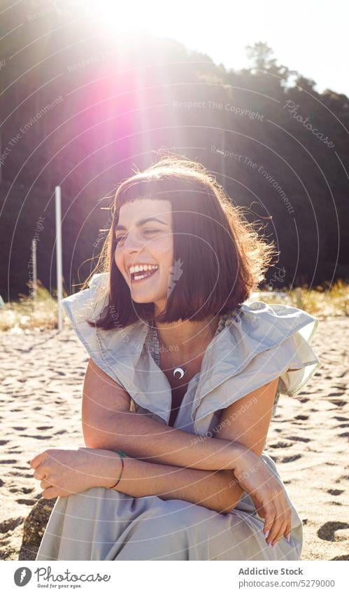 Delighted woman smiling on sandy seashore in sunlight beach smile happy holiday vacation summer tourist cheerful positive nature female young brunette style