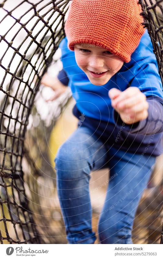 Happy boy walking in net on playground child smile weekend positive joy childhood having fun kid hat happy cheerful adorable park cute street little