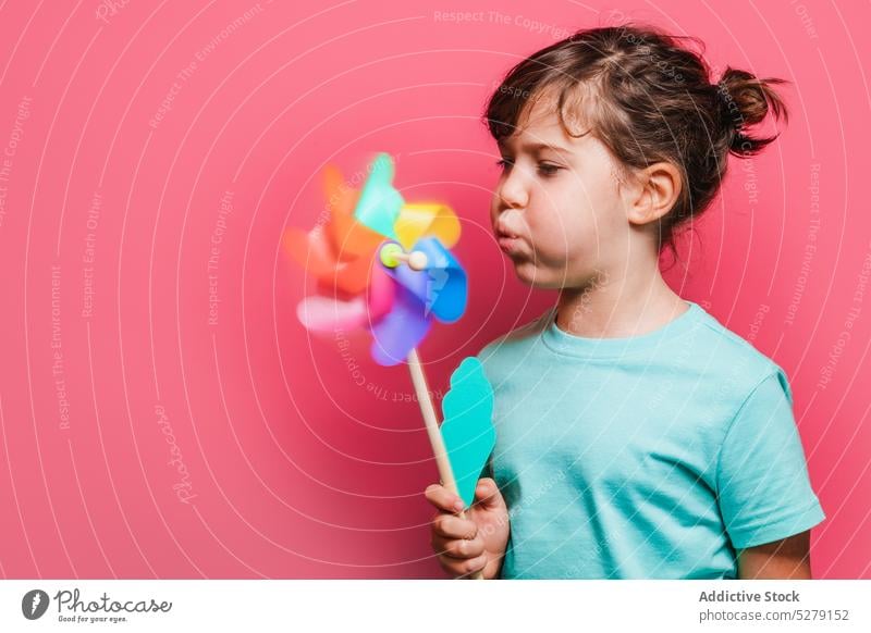 Funny kid blowing on pinwheel girl rainbow play leisure entertain interest game funny playful cheerful toy child individuality childhood sweet expressive