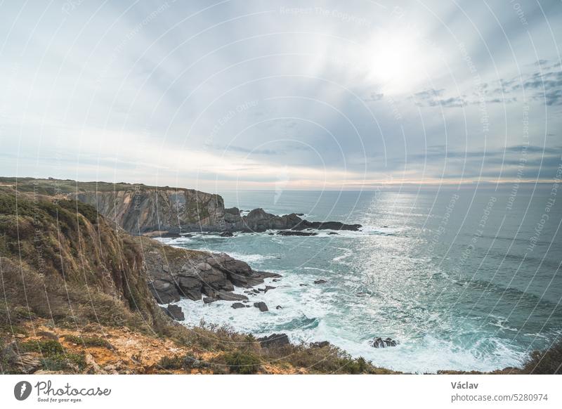 Rugged rock and cliff coastline on the Atlantic Ocean near the town of Odeceixe in the west of Portugal in the famous tourist region of the Algarve. Sunset