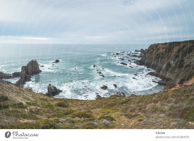 Rugged rock and cliff coastline on the Atlantic Ocean near the town of Odeceixe in the west of Portugal in the famous tourist region of the Algarve. Sunset