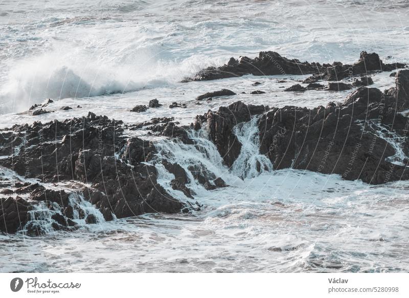 Stormy ocean is proving its strength. Waves crash against a rock during sunset in the Odemira region, western Portugal. Wandering along the Fisherman Trail, Rota Vicentina