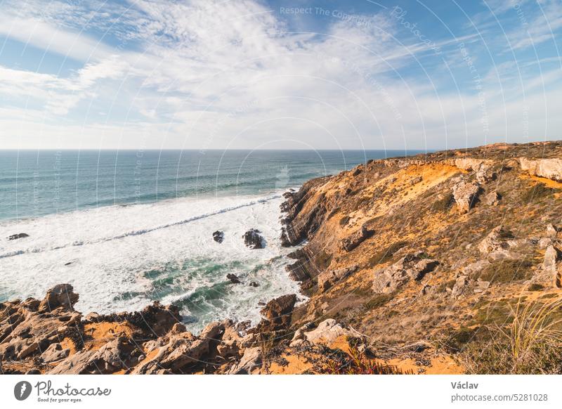 Cliffs under the onslaught of the sun are slowly crumbling into the Atlantic Ocean in the Odemira region, western Portugal. Wandering along the Fisherman Trail, Rota Vicentina