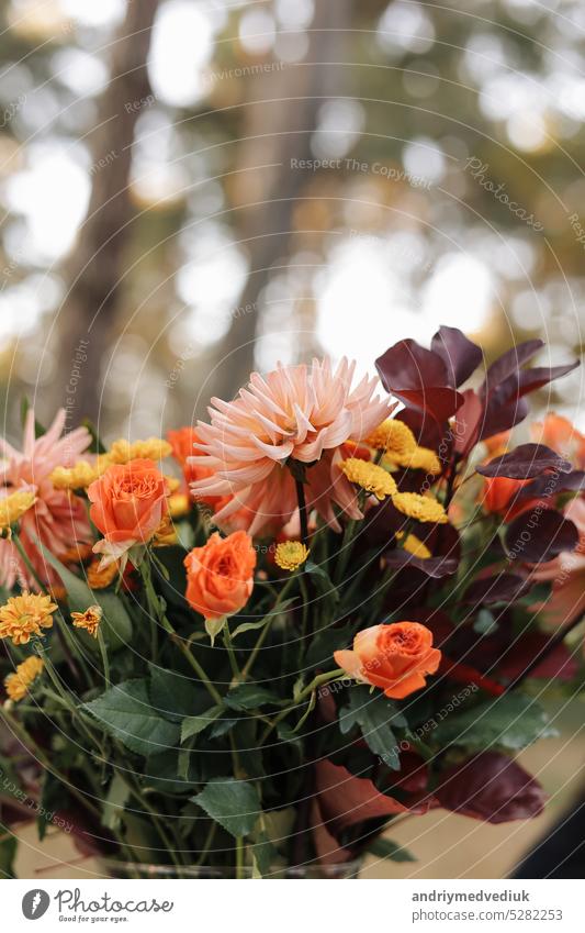 Beautiful autumnal arrangement of flowers in a glass vase outdoors. Autumn bouquet with garden flowers. Colorful dahlia and chrysanthemum.Gift for anniversary, birthday, mothers day.