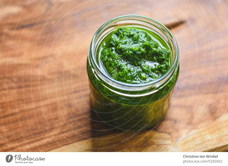 A jar of homemade wild garlic pesto stands on a wooden plate Self-made Wild garlic pesto Club moss Italien pesto Supply Food Vegetarian diet Organic produce