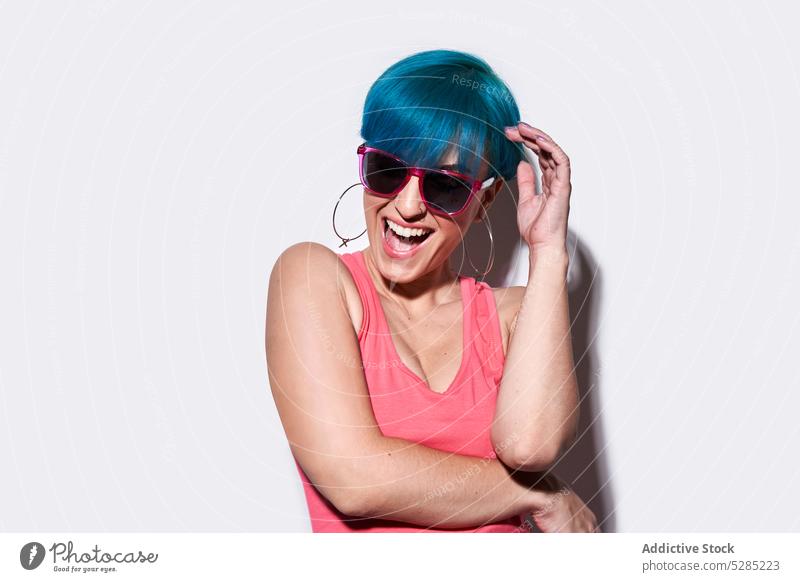 Cheerful woman with blue hair in studio excited having fun active sunglasses studio shot cheerful unique joy eyewear smile positive happy female young free time