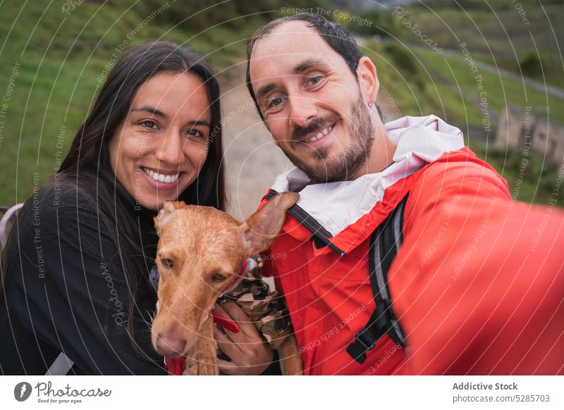 Happy couple taking selfie with dog on road happy smile tourist pet take photo path highland together relationship hug nature cheerful basenji asturias spain