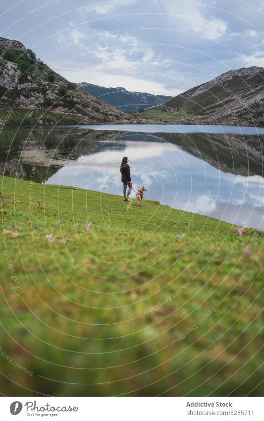 Unrecognizable woman standing near mountain lake with dog traveler tourist pet valley admire highland explore landscape asturias spain female nature wanderlust