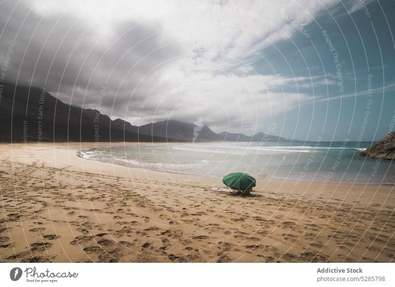 Sandy beach with umbrella near mountains sand sea parasol picturesque endless tourism water nature ocean landscape scenic coastline breathtaking spectacular