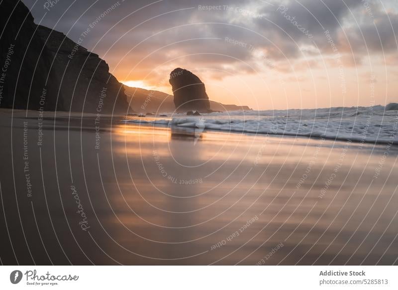 Stormy sea with foamy waves beach sunset cliff seashore ocean landscape seascape coast nature sundown picturesque sand sky scenic spain evening coastline