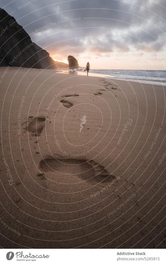 Anonymous woman taking photo on sandy beach stroll sunset photo camera walk traveler take photo sea seashore vacation coast female sundown wave ocean nature